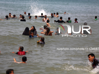 Palestinians are enjoying the beach on a hot day, amid the ongoing conflict between Israel and Hamas, in Deir Al-Balah, in the central Gaza...