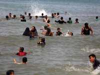 Palestinians are enjoying the beach on a hot day, amid the ongoing conflict between Israel and Hamas, in Deir Al-Balah, in the central Gaza...