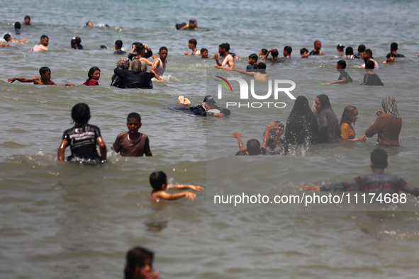 Palestinians are enjoying the beach on a hot day, amid the ongoing conflict between Israel and Hamas, in Deir Al-Balah, in the central Gaza...