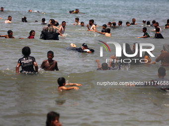 Palestinians are enjoying the beach on a hot day, amid the ongoing conflict between Israel and Hamas, in Deir Al-Balah, in the central Gaza...