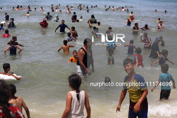 Palestinians are enjoying the beach on a hot day, amid the ongoing conflict between Israel and Hamas, in Deir Al-Balah, in the central Gaza...