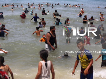 Palestinians are enjoying the beach on a hot day, amid the ongoing conflict between Israel and Hamas, in Deir Al-Balah, in the central Gaza...