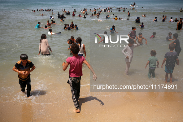 Palestinians are enjoying the beach on a hot day, amid the ongoing conflict between Israel and Hamas, in Deir Al-Balah, in the central Gaza...