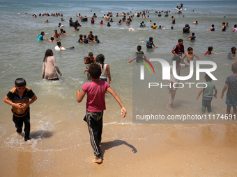 Palestinians are enjoying the beach on a hot day, amid the ongoing conflict between Israel and Hamas, in Deir Al-Balah, in the central Gaza...