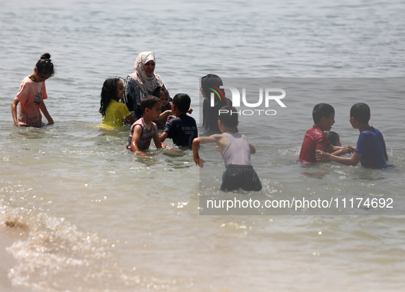 Palestinians are enjoying the beach on a hot day, amid the ongoing conflict between Israel and Hamas, in Deir Al-Balah, in the central Gaza...