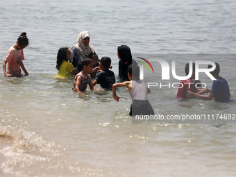 Palestinians are enjoying the beach on a hot day, amid the ongoing conflict between Israel and Hamas, in Deir Al-Balah, in the central Gaza...