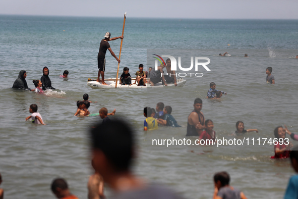 Palestinians are enjoying the beach on a hot day, amid the ongoing conflict between Israel and Hamas, in Deir Al-Balah, in the central Gaza...