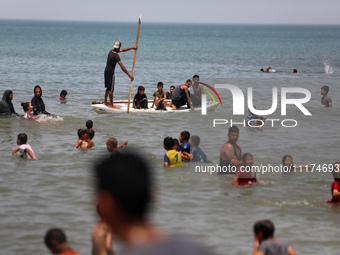 Palestinians are enjoying the beach on a hot day, amid the ongoing conflict between Israel and Hamas, in Deir Al-Balah, in the central Gaza...