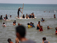 Palestinians are enjoying the beach on a hot day, amid the ongoing conflict between Israel and Hamas, in Deir Al-Balah, in the central Gaza...