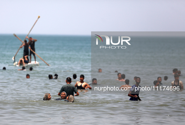 Palestinians are enjoying the beach on a hot day, amid the ongoing conflict between Israel and Hamas, in Deir Al-Balah, in the central Gaza...