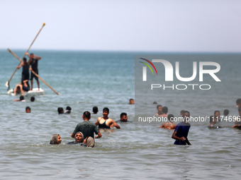 Palestinians are enjoying the beach on a hot day, amid the ongoing conflict between Israel and Hamas, in Deir Al-Balah, in the central Gaza...