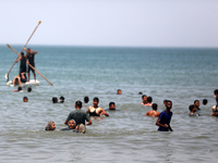 Palestinians are enjoying the beach on a hot day, amid the ongoing conflict between Israel and Hamas, in Deir Al-Balah, in the central Gaza...