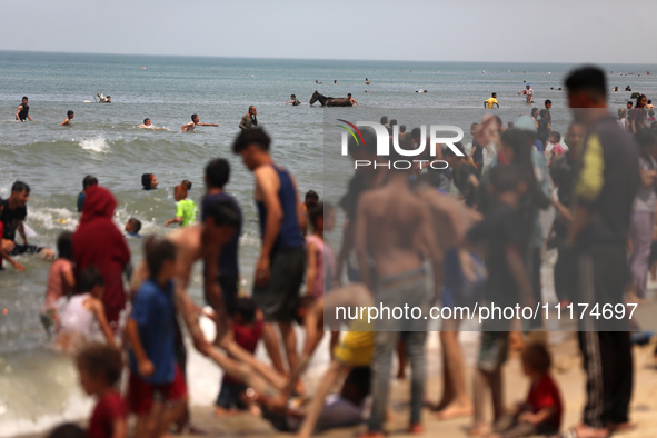 Palestinians are enjoying the beach on a hot day, amid the ongoing conflict between Israel and Hamas, in Deir Al-Balah, in the central Gaza...