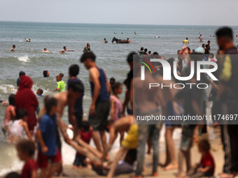 Palestinians are enjoying the beach on a hot day, amid the ongoing conflict between Israel and Hamas, in Deir Al-Balah, in the central Gaza...