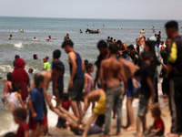 Palestinians are enjoying the beach on a hot day, amid the ongoing conflict between Israel and Hamas, in Deir Al-Balah, in the central Gaza...