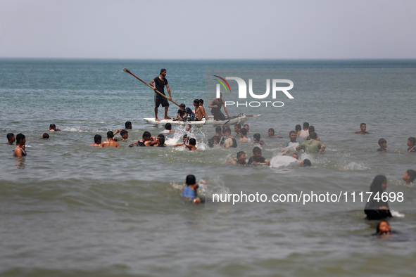 Palestinians are enjoying the beach on a hot day, amid the ongoing conflict between Israel and Hamas, in Deir Al-Balah, in the central Gaza...