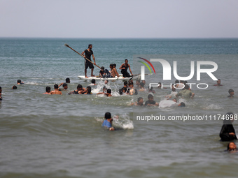 Palestinians are enjoying the beach on a hot day, amid the ongoing conflict between Israel and Hamas, in Deir Al-Balah, in the central Gaza...