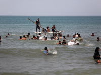 Palestinians are enjoying the beach on a hot day, amid the ongoing conflict between Israel and Hamas, in Deir Al-Balah, in the central Gaza...