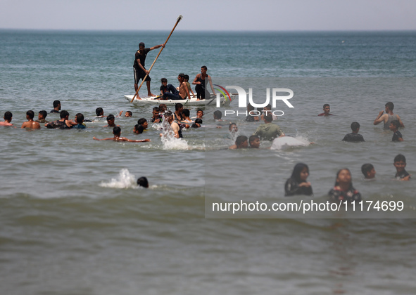 Palestinians are enjoying the beach on a hot day, amid the ongoing conflict between Israel and Hamas, in Deir Al-Balah, in the central Gaza...