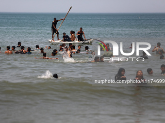 Palestinians are enjoying the beach on a hot day, amid the ongoing conflict between Israel and Hamas, in Deir Al-Balah, in the central Gaza...