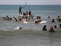 Palestinians are enjoying the beach on a hot day, amid the ongoing conflict between Israel and Hamas, in Deir Al-Balah, in the central Gaza...