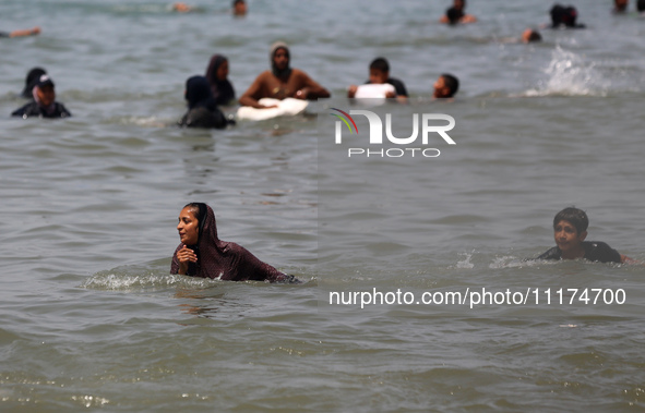 Palestinians are enjoying the beach on a hot day, amid the ongoing conflict between Israel and Hamas, in Deir Al-Balah, in the central Gaza...