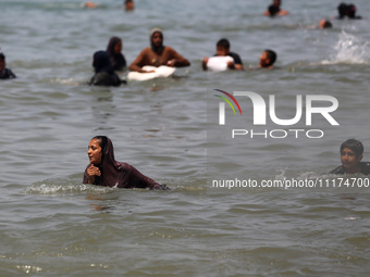 Palestinians are enjoying the beach on a hot day, amid the ongoing conflict between Israel and Hamas, in Deir Al-Balah, in the central Gaza...