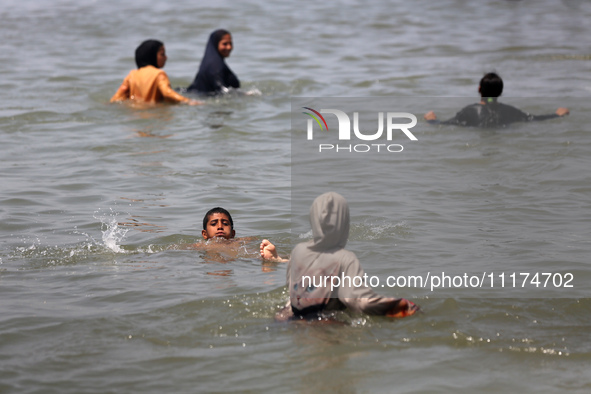 Palestinians are enjoying the beach on a hot day, amid the ongoing conflict between Israel and Hamas, in Deir Al-Balah, in the central Gaza...