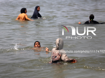 Palestinians are enjoying the beach on a hot day, amid the ongoing conflict between Israel and Hamas, in Deir Al-Balah, in the central Gaza...