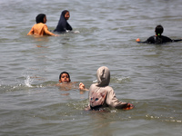 Palestinians are enjoying the beach on a hot day, amid the ongoing conflict between Israel and Hamas, in Deir Al-Balah, in the central Gaza...