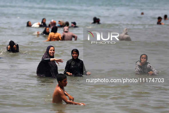 Palestinians are enjoying the beach on a hot day, amid the ongoing conflict between Israel and Hamas, in Deir Al-Balah, in the central Gaza...