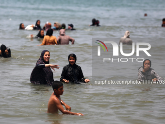 Palestinians are enjoying the beach on a hot day, amid the ongoing conflict between Israel and Hamas, in Deir Al-Balah, in the central Gaza...