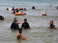 Palestinians are enjoying the beach on a hot day, amid the ongoing conflict between Israel and Hamas, in Deir Al-Balah, in the central Gaza...