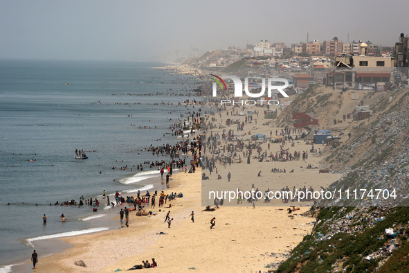 Palestinians are enjoying the beach on a hot day, amid the ongoing conflict between Israel and Hamas, in Deir Al-Balah, in the central Gaza...