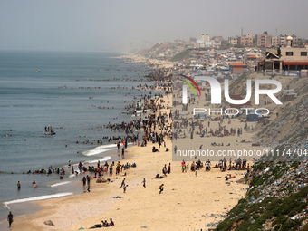 Palestinians are enjoying the beach on a hot day, amid the ongoing conflict between Israel and Hamas, in Deir Al-Balah, in the central Gaza...