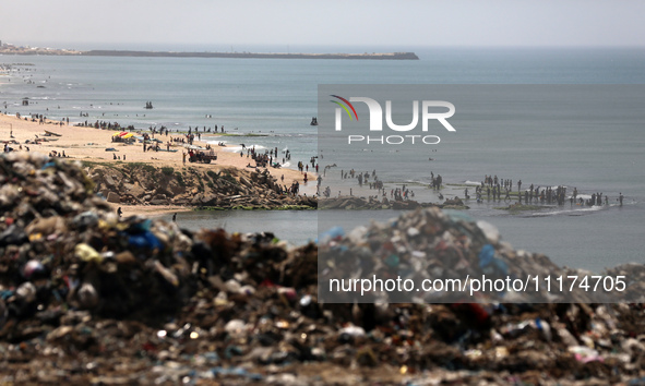 Palestinians are enjoying the beach on a hot day, amid the ongoing conflict between Israel and Hamas, in Deir Al-Balah, in the central Gaza...