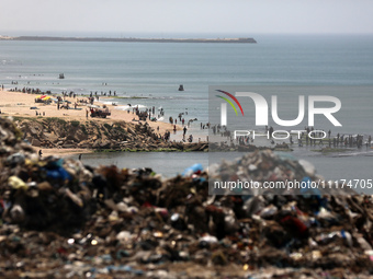 Palestinians are enjoying the beach on a hot day, amid the ongoing conflict between Israel and Hamas, in Deir Al-Balah, in the central Gaza...