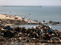 Palestinians are enjoying the beach on a hot day, amid the ongoing conflict between Israel and Hamas, in Deir Al-Balah, in the central Gaza...