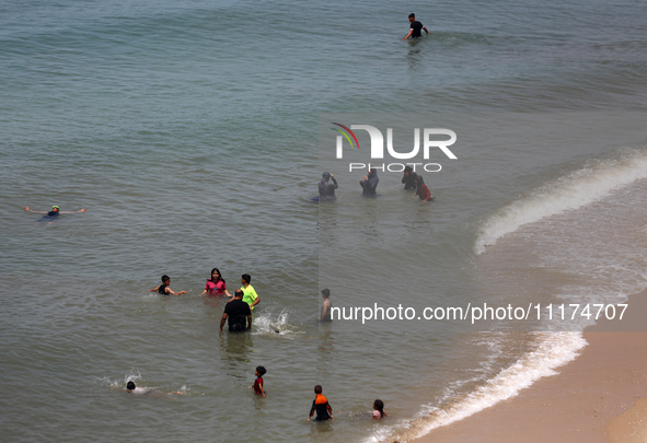 Palestinians are enjoying the beach on a hot day, amid the ongoing conflict between Israel and Hamas, in Deir Al-Balah, in the central Gaza...