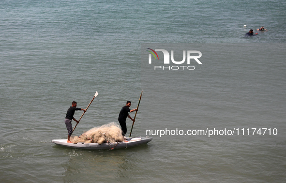 Palestinian fishermen are working in the sea amid the ongoing conflict between Israel and Hamas in Deir Al-Balah, in the central Gaza Strip,...