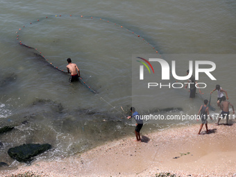 Palestinian fishermen are working in the sea amid the ongoing conflict between Israel and Hamas in Deir Al-Balah, in the central Gaza Strip,...