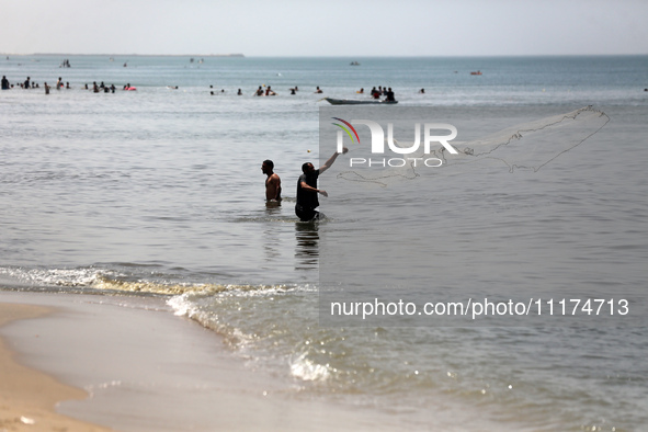 Palestinian fishermen are working in the sea amid the ongoing conflict between Israel and Hamas in Deir Al-Balah, in the central Gaza Strip,...