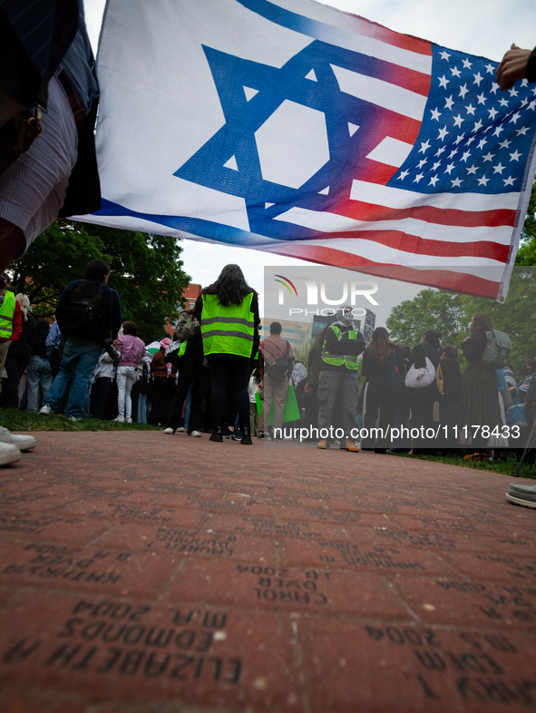 Counter-protesters silently display an Israeli/American flag during a rally at an encampment for Palestine set up by George Washington Unive...