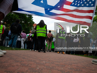 Counter-protesters silently display an Israeli/American flag during a rally at an encampment for Palestine set up by George Washington Unive...