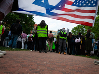 Counter-protesters silently display an Israeli/American flag during a rally at an encampment for Palestine set up by George Washington Unive...