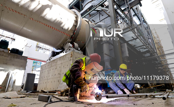 Construction workers are welding pipes for an incinerator at the incineration workshop of the Zhangye Hazardous Waste (Solid Waste) Disposal...