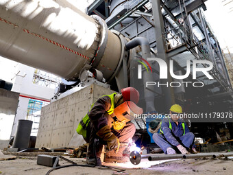 Construction workers are welding pipes for an incinerator at the incineration workshop of the Zhangye Hazardous Waste (Solid Waste) Disposal...