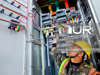 A construction worker is installing electrical equipment at the incineration workshop of the Zhangye Hazardous Waste (solid waste) Disposal...