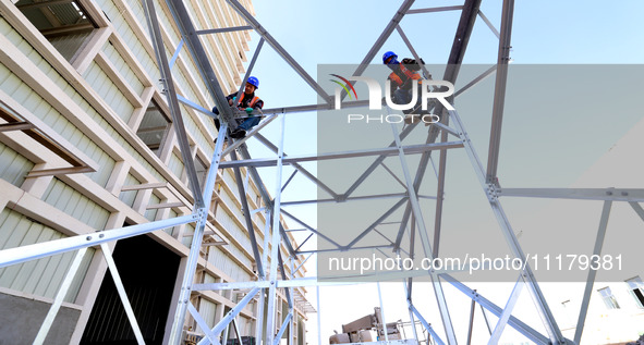 Construction workers are linking a steel tower at the construction site of the Zhangye Waste Disposal and Resource Utilization Center in Zha...