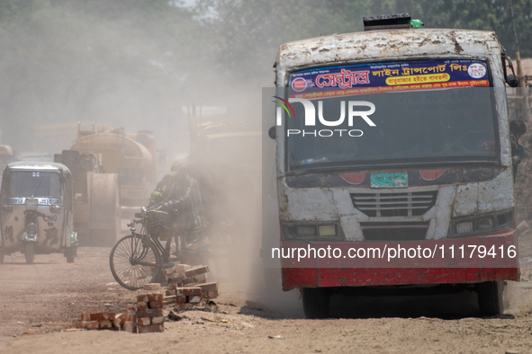 People are walking along a dusty, busy road in Dhaka, Bangladesh, on April 26, 2024. 